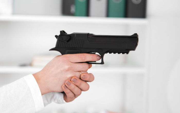 Woman aiming hand gun in home
